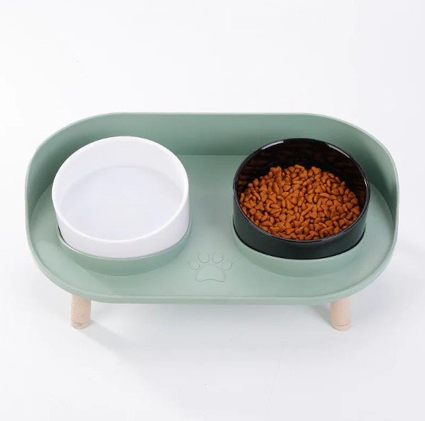 Green base with black and white bowls — elevated double feeder for dogs and cats.
