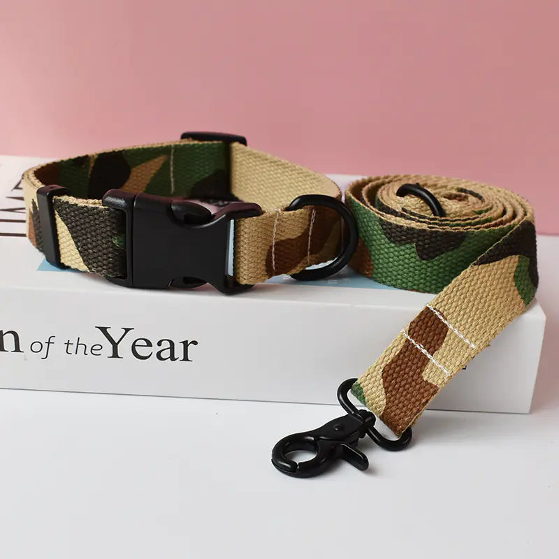 Camouflage dog collar and leash set on a white surface with a pink background